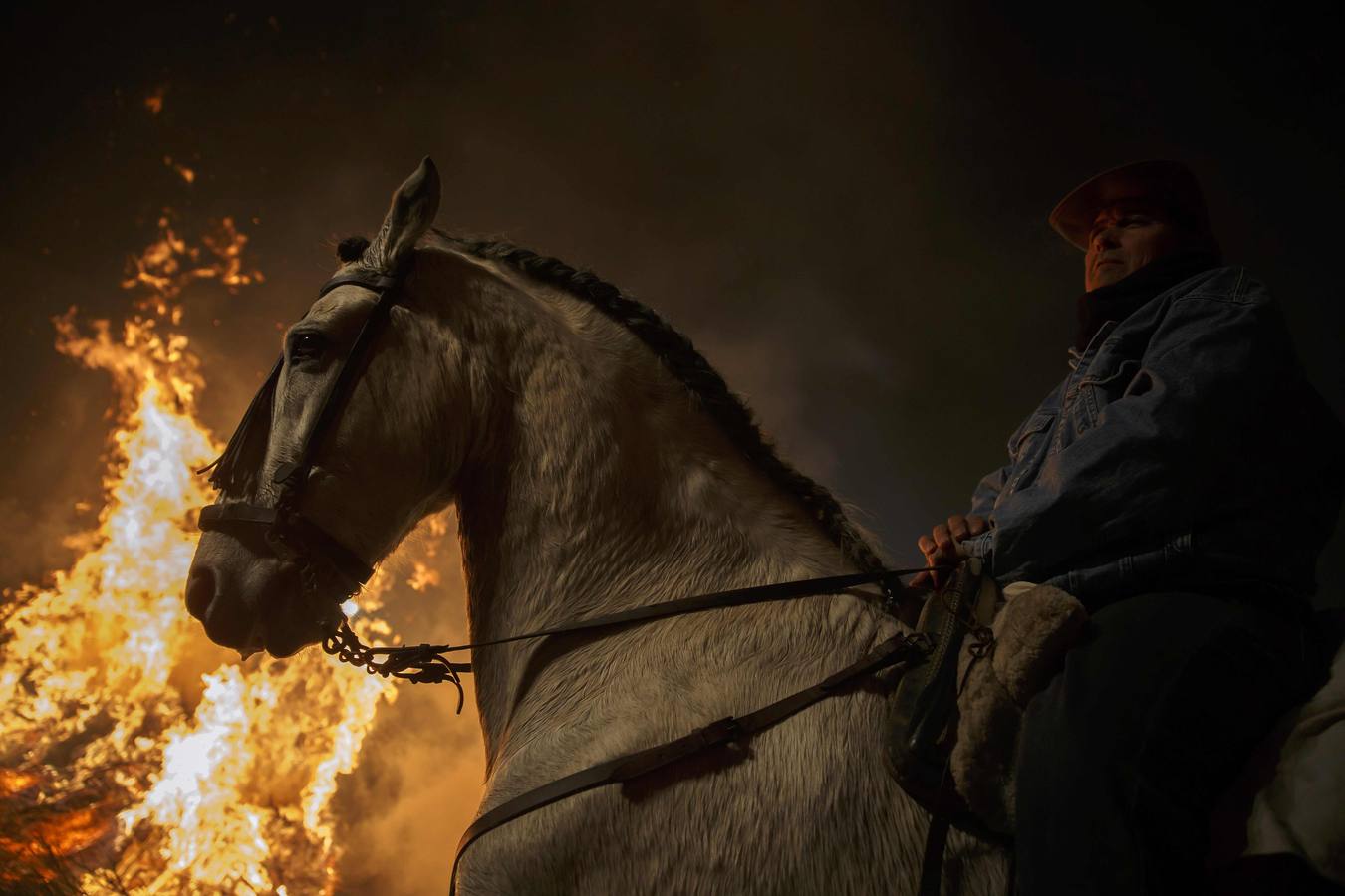 Sábado, 17 de enero: La pequeña localidad abulense de San bartolomé de Pinares volvió a vivir una noche mágica, sumergida bajo una espesa nube de humo que sirvió para purificar al centenar de caballos que pasó por la veintenas de luminarias distribuidadas por las empinadas calles del pueblo. Fotografia: Juan Medina / Reuters