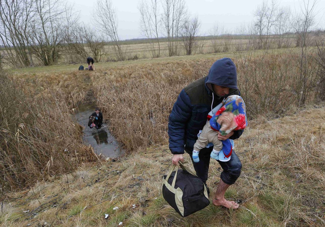 Un hombre de Kosovo lleva a su bebé mientras cruza ilegalmente la frontera entre Hungría y Serbia, cerca del pueblo de Ásotthalom. Fotografía: REUTERS / Lazlo Balogh.