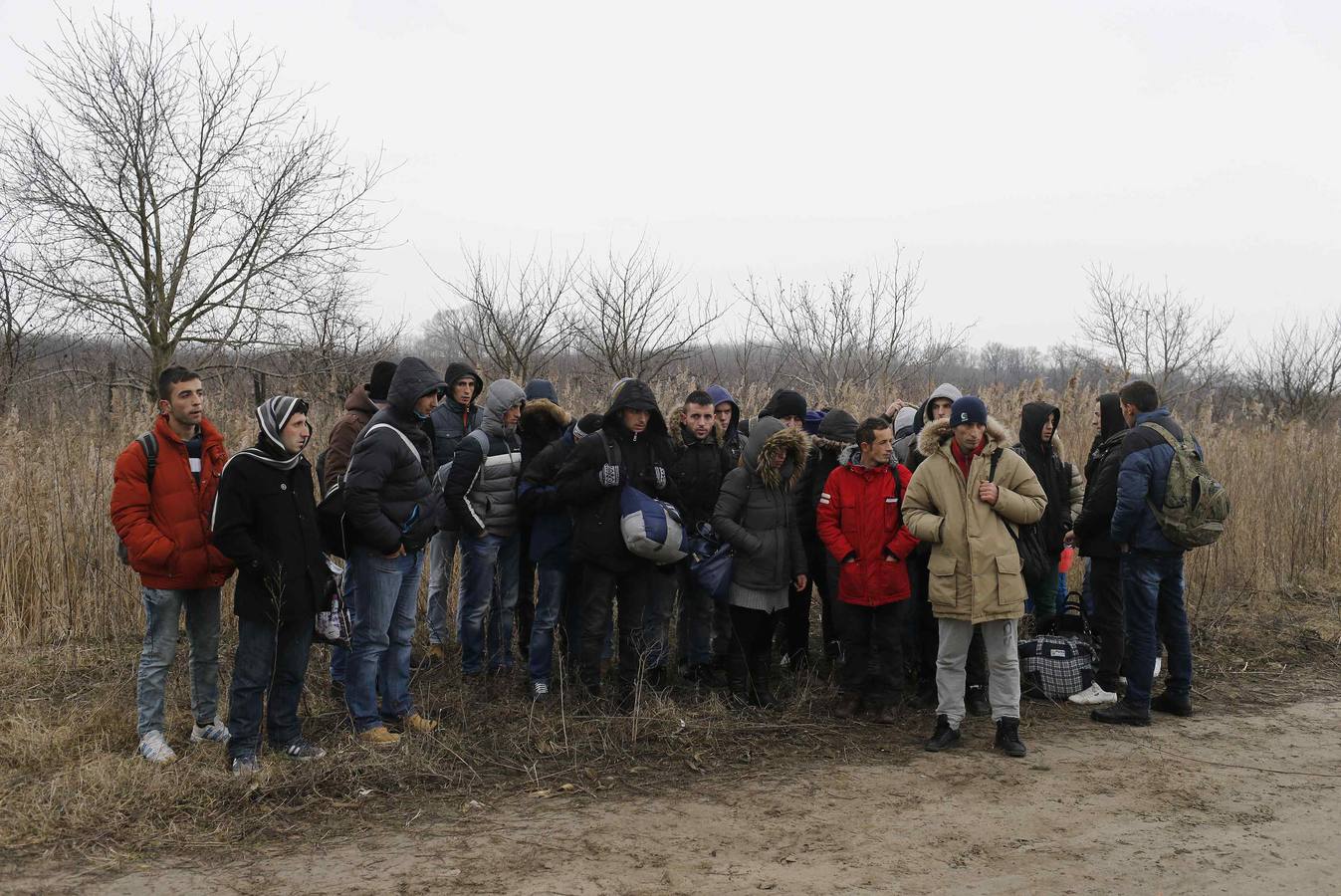 Un policía serbio recoge la documentación de un grupo de habitantes de Kosovo, después de que fueran detenidos cuando trataban de cruzar la frontera hacia Hungría, cerca de la ciudad de Subotica. Fotografía: REUTERS / Marko Djurica