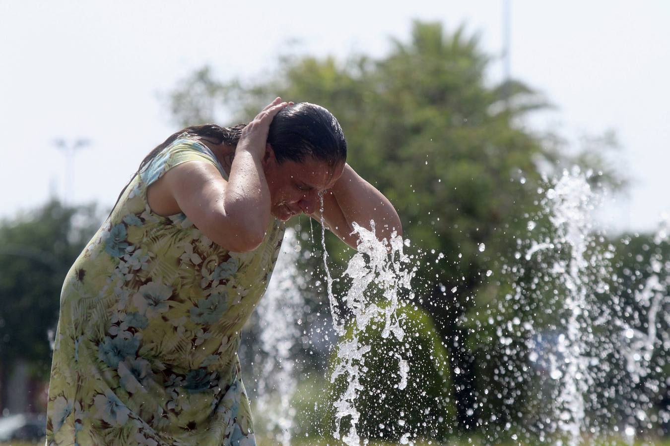 Una mujer se refresca en una de las fuentes de Córdoba.