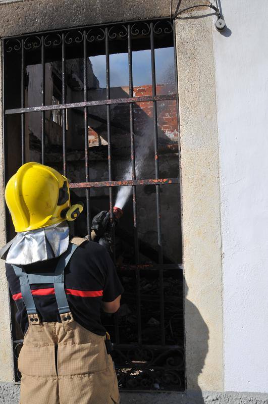 Un bombero del Sepei apaga el fuego en una casa de Hoyos