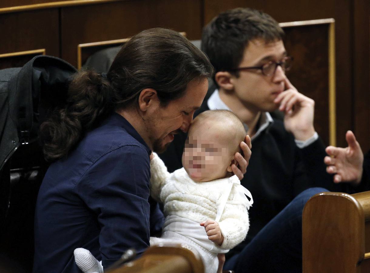 El líder de Podemos, Pablo Iglesias, con la hija de la diputada de su partido Carolina Bescansa en sus brazos en su escaño del Congreso.