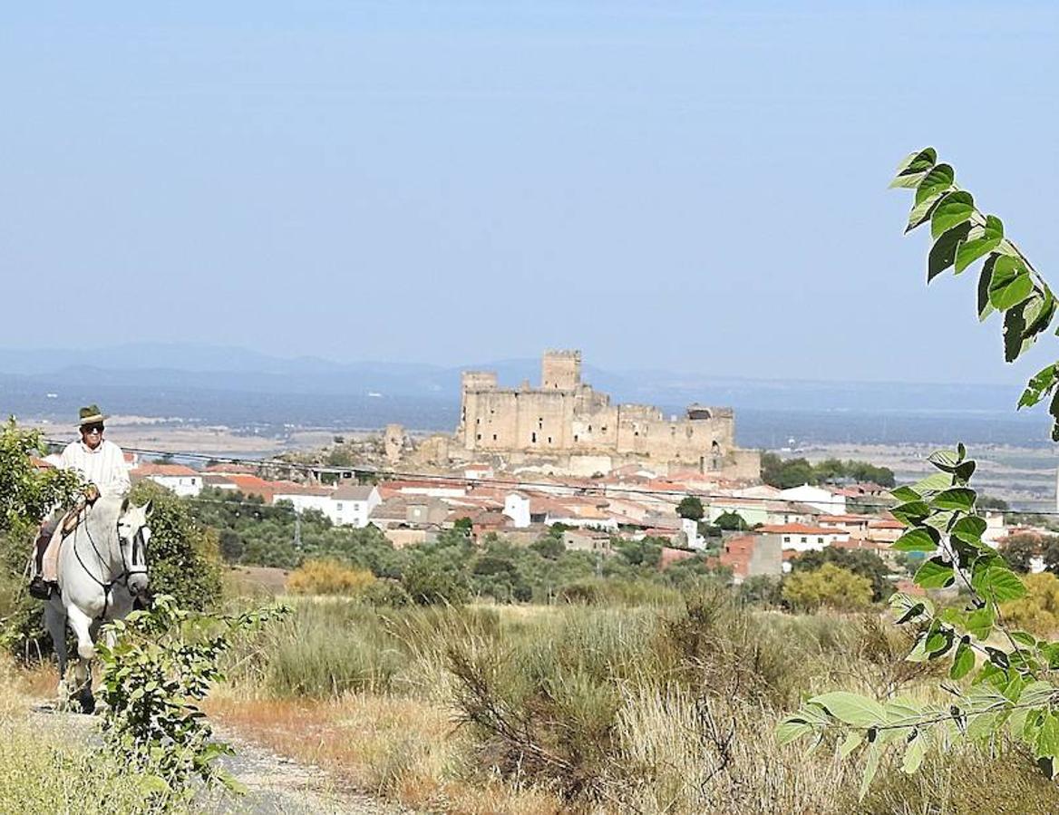 Un jinete cabalga, con el castillo de Belvís de Monroy al fondo.