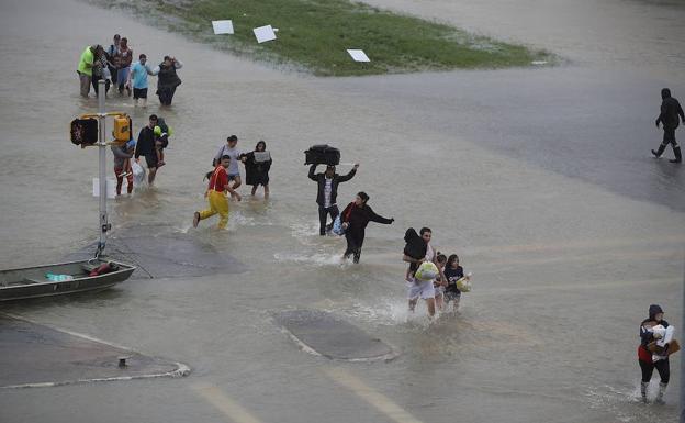 Gente caminado por las calles inundadas de Houston. 