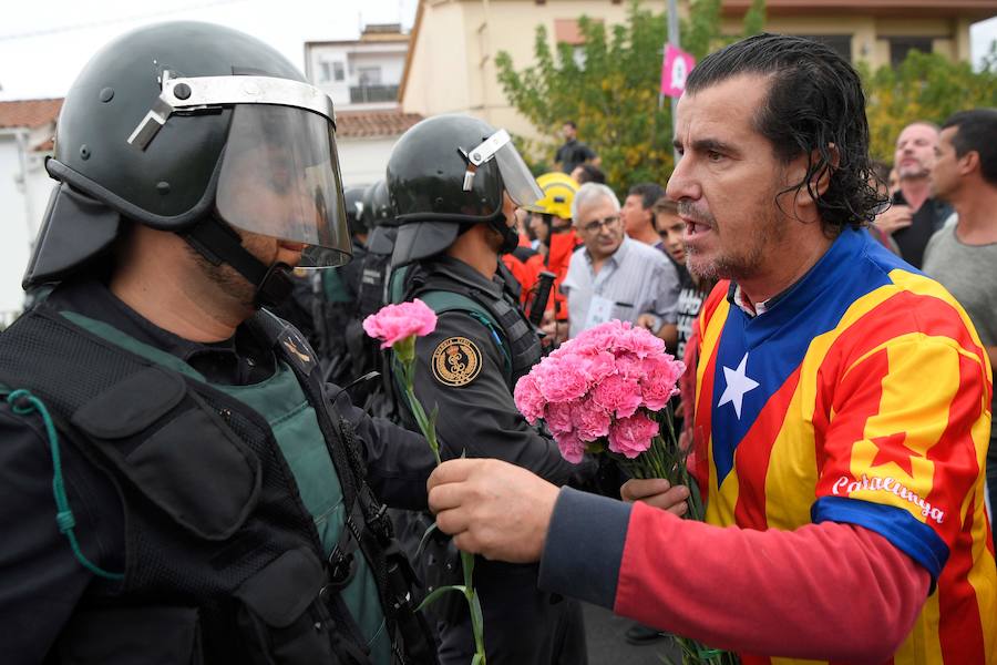 Un hombre ataviado con una camiseta con la estelada ofrece un clavel a un agente de la Guardia Civil.