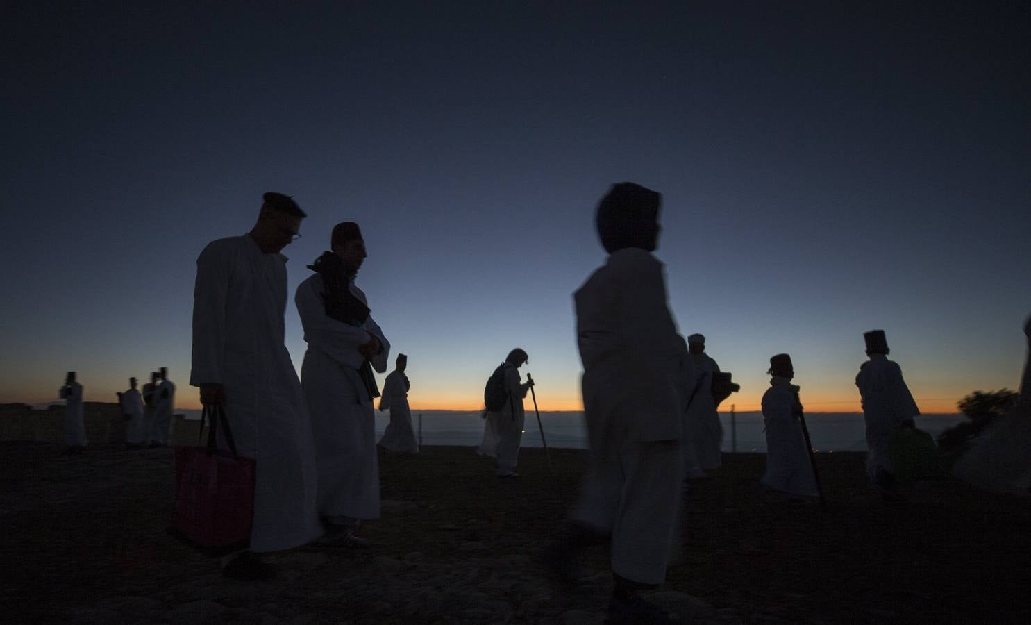 Miembros de la comunidad samaritana caminan hacia la cima del Monte Guerizín al amanecer en Nablus (Palestina), con motivo de la celebración del Sukot o fiesta de los tabernáculos.
