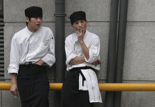 Dos trabajadores japoneses apuran un cigarrillo a la puerta de su empresa. :: ap