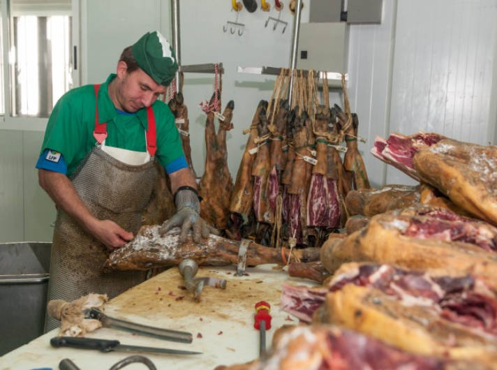 Un trabajador manipula jamones en la fábrica de IberPro de Torrecillas de la Tiesa. /