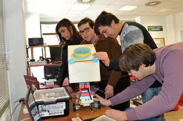 Los cuatro jóvenes examinan el robot ganador en la Roborave Ibérica. :: e. d.