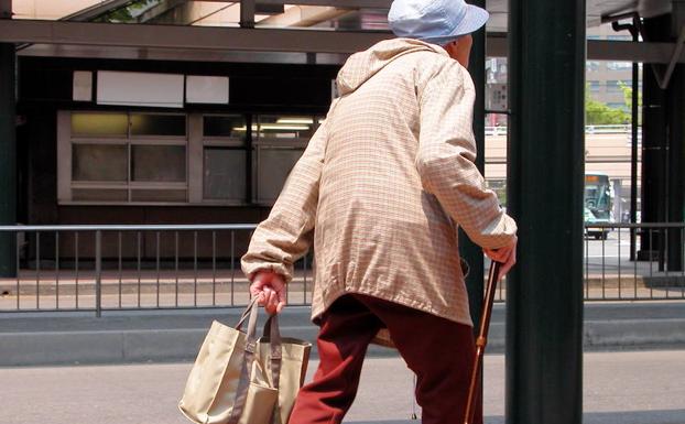 Una anciana -ajena a la información- camina lentamente sujetando su bolso.