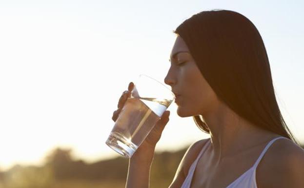 Una mujer bebe agua.