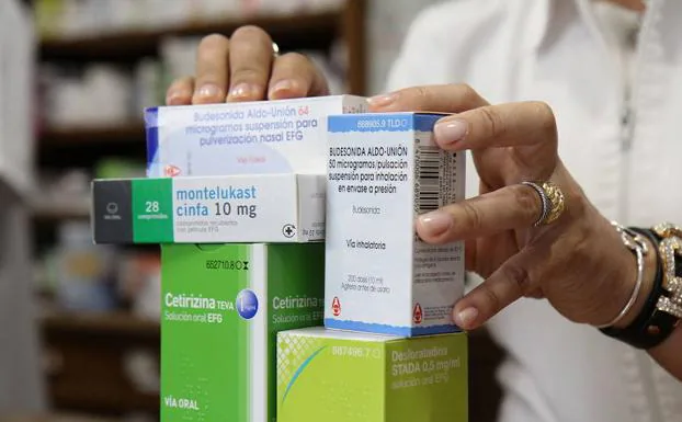 Una farmacéutica entrega un lote de medicamentos a un usuario.