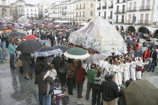 Paso de la Sagrada Cena protegida por la lluvia en su recorrido por la plaza Mayor de Cáceres. :: Hoy