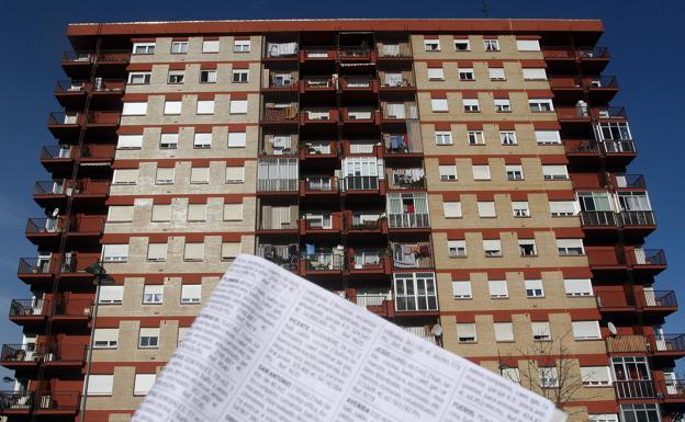 Anuncios de alquiler de pisos frente a un bloque de vivienda.