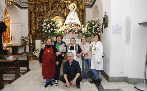 Imagen principal - El equipo de ornato, ayer junto a la patrona y una vecina de Caleros encala su fachada.;