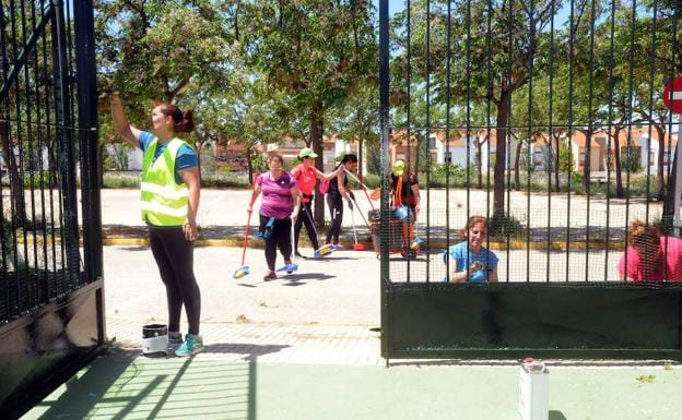 Cuadrilla de operarias del Aepsa pintando la puerta de la piscina municipal de Calamonte. :: 