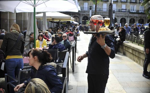 Un camarero, sirviendo bebidas en la terraza.