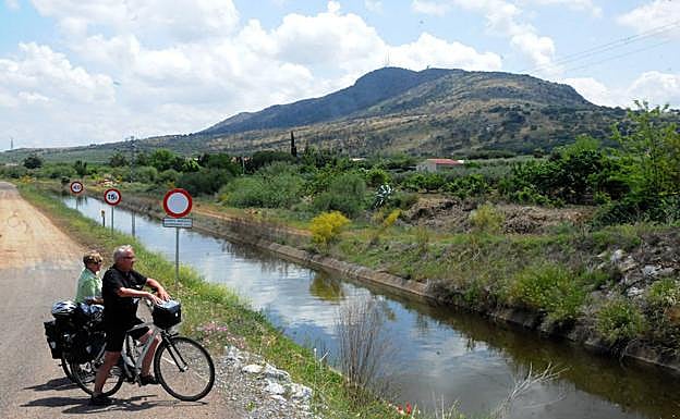 Dos cicloturistas ingleses miran el ramal del Canal de Lobón que se encuentra a la entrada de Arroyo de San Serván, al lado de la capital de Extremadura
