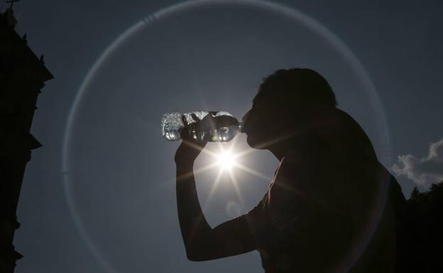 Un hombre bebe agua para mitigar el intenso calor. 