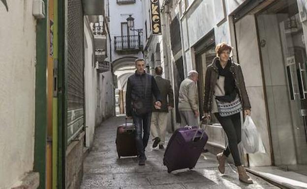 Turistas pasan con sus maletas por una calle de Cáceres:: HOY