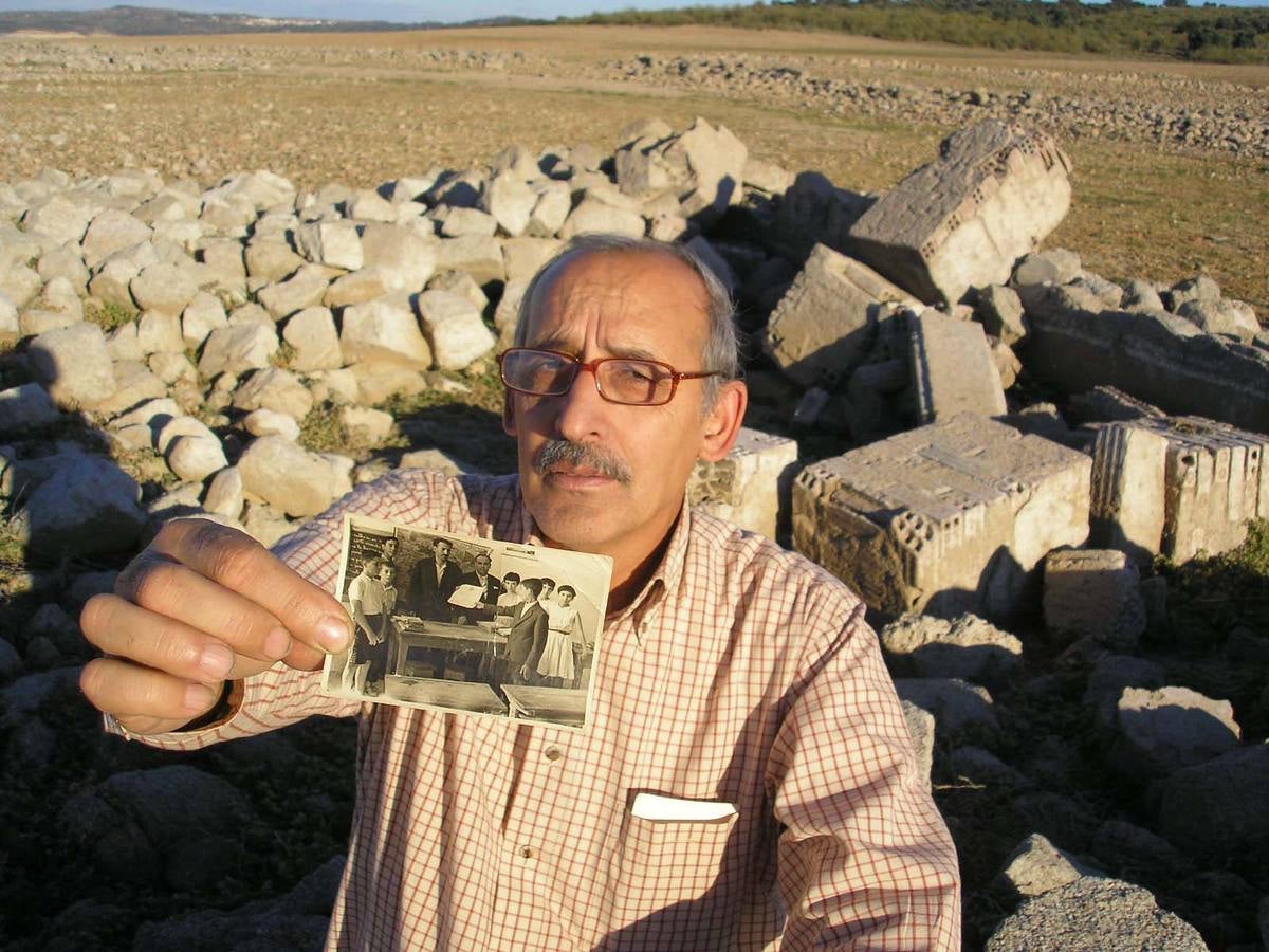 20-Sequía de 2007. Felipe Rubio muestra una fotografía en la que recibe un diploma, cuando aún era niño. Tras él un montón de escombros que pertenecen a la misma aula de la foto.