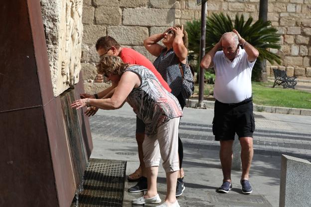 Turistas catalanes se refrescan en la fuente del Anas, cerca del Puente Romano de Mérida. ::