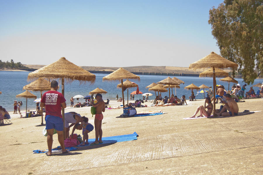 Bañistas en la zona con suelo de hormigón. Al fondo a la derecha, el embalse.