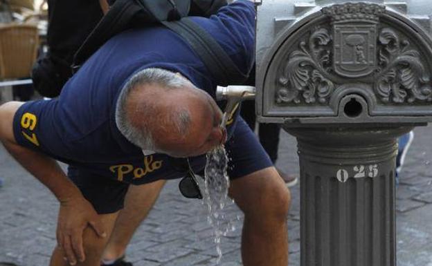 Un hombre bebe agua en una fuente