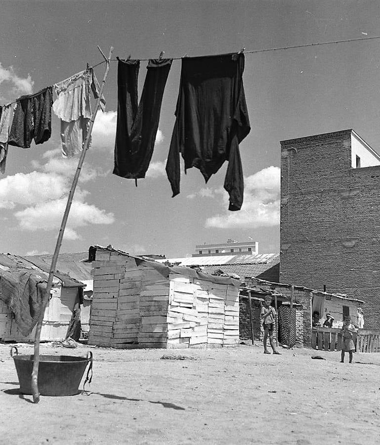 Ropa tendida y niños junto a chabolas de madera.(Fotografía Juan Pando Barrero/Fototeca Nacional).