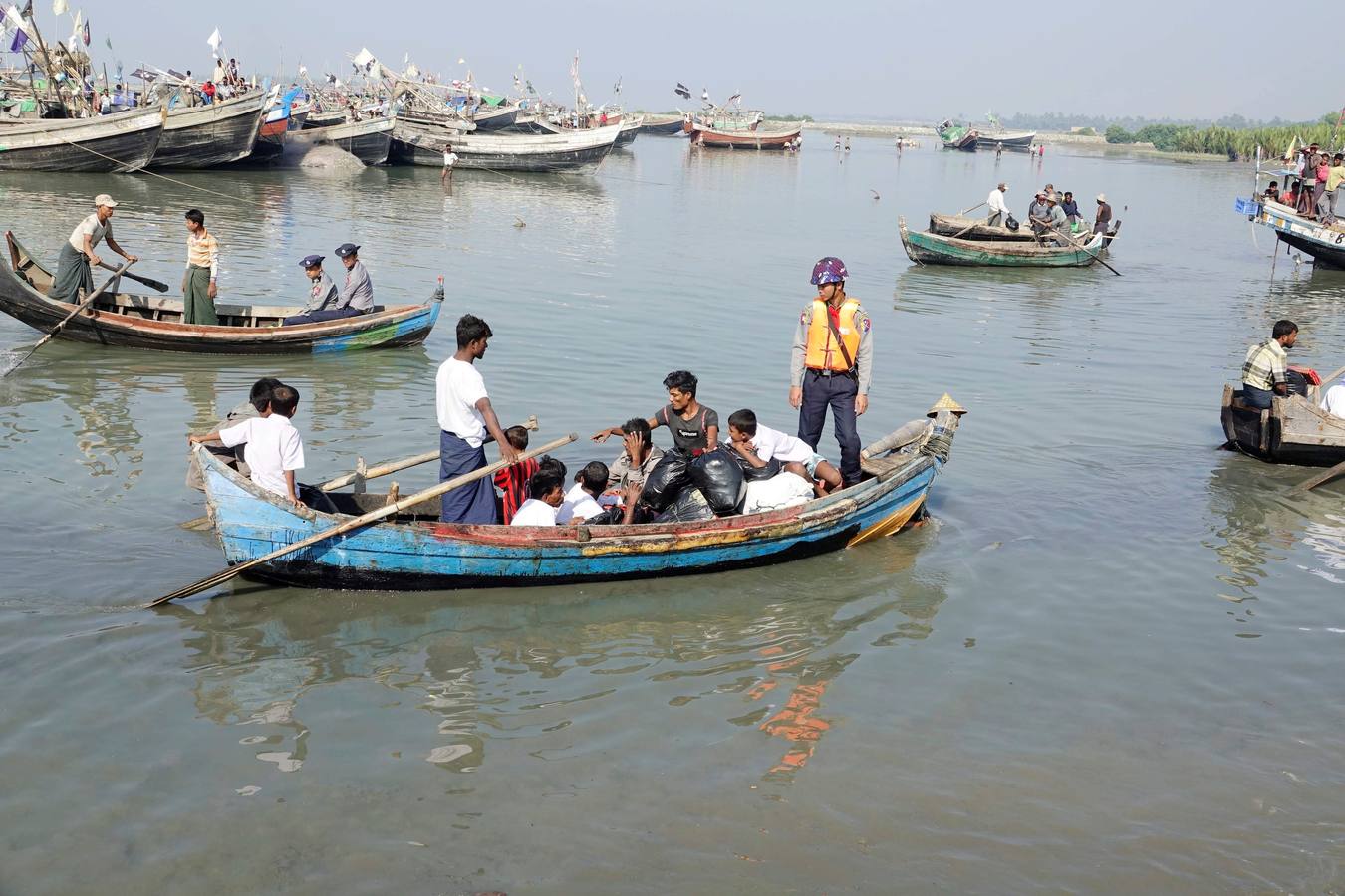 Policías birmanos escoltan al grupo de 106 rohinyás de vuelta a Sittwe en el estado de Rakáin (Birmania). El pasado 16 de noviembre, el barco en el que viajaban los 106 rohinyás encalló en la costa cerca de Rangún, con uno de sus ocupantes muerto, cuando trataba de llegar a Malasia. 