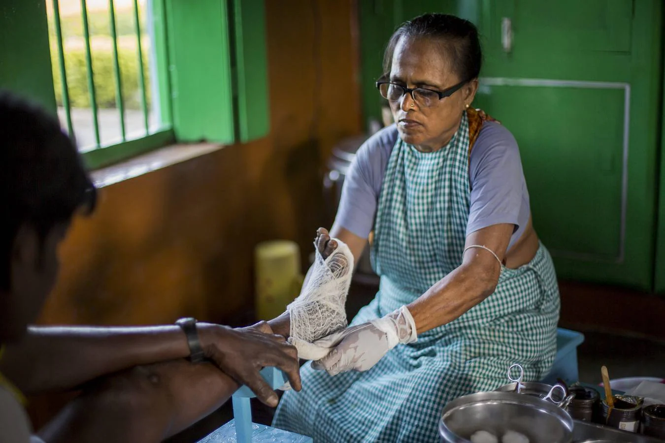 La lepra es una de las enfermedades infecciosas más antiguas que el hombre conoce. Según la Organización Mundial de la Salud (OMS), afecta principalmente la piel, los nervios, los ojos y el tracto respiratorio superior, pero la enfermedad es curable y el tratamiento en sus primeras etapas puede prevenir la discapacidad. Fuera de la ciudad de Titagarh, en el estado indio de Bengala Occidental, la Madre Teresa estableció en 1958 el Centro de Lepra Gandhiji Prem Nivas. Dirigido por sus Misioneras de la Caridad, el centro fue construido para una comunidad existente de personas con lepra. Ahora, más de 1000 personas, los afectados y sus familias, viven y trabajan en las instalaciones. Los residentes que se han recuperado de la enfermedad trabajan como tejedores en el centro. Producen los saris azules y blancos que usan las monjas de la Caridad. Los niños de los pacientes reciben educación gratuita en el centro, que también ofrece comida gratis, atención médica básica y tratamiento psicológico a sus residentes. La instalación se lleva a cabo con la ayuda de donaciones y el apoyo de la OMS, que en abril de 2016 lanzó la Estrategia Global de Lepra 2016-2020, dirigida a la eliminación mundial de la enfermedad. Gandhiji Prem Nivas participa en el programa de la OMS junto con otros hospitales en la India. Ofrece tratamientos recomendados por la OMS no solo para pacientes que residen en el centro, sino también para otras personas afectadas por la lepra que necesitan atención médica. 