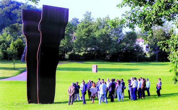 Un grupo de visitantes contempla la escultura 'Buscando la luz', que domina la campa de Zabalaga.