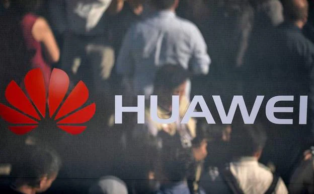 Fotografía de archivo realizada el 16 de octubre de 2019 que muestra a peatones que se reflejan en un espejo con el logotipo de la empresa china de telecomunicaciones Huawei en Múnich. 