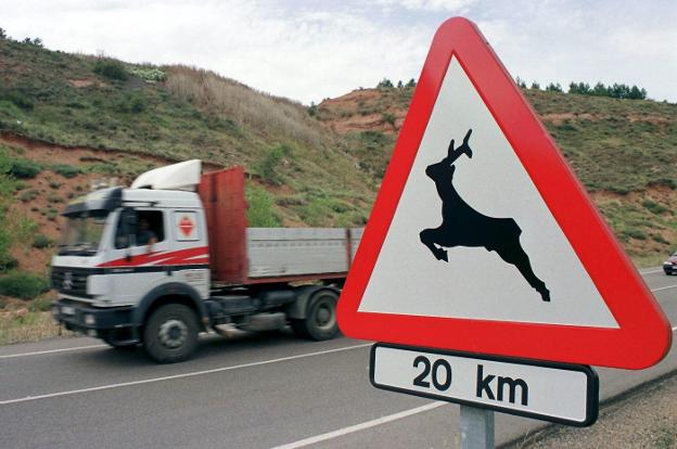 Un camión pasa junto a una señal que alerta del peligro de animales sueltos. 