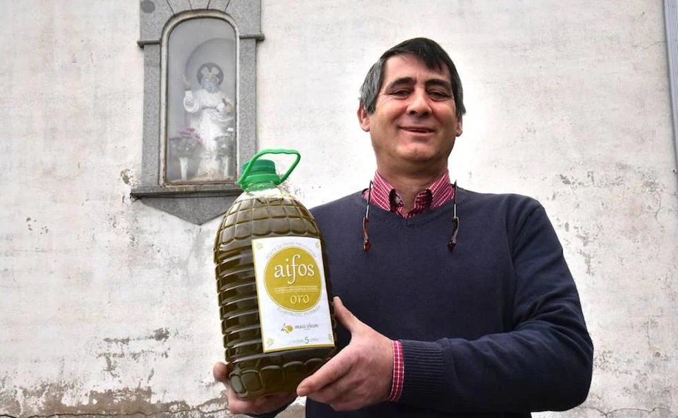 Juan M. Martín, con una botella de su aceite ante la imagen de Dios Padre.