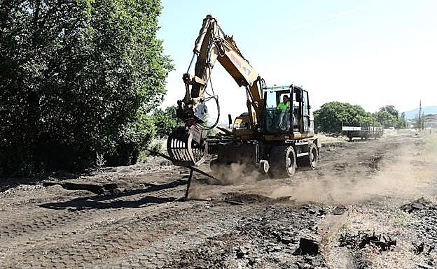 Una excavadora retira antiguos carriles y traviesas; al fondo, estación de Almorchón. :: 
