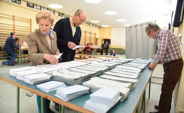 Dos personas escogen papeleta en un colegio electoral en Plasencia.