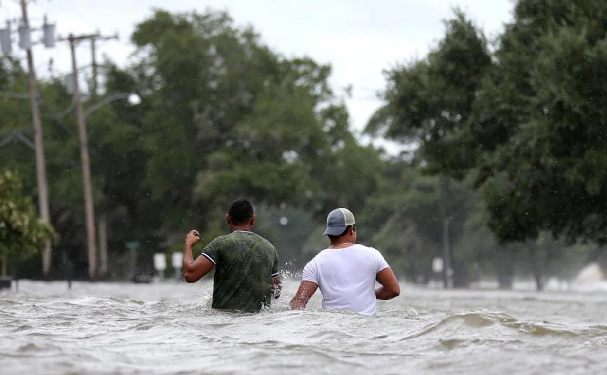 Dos hombres luchan contra los efectos del huracán Barry. 