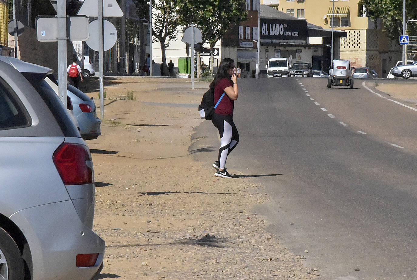 Una joven cruza la avenida Ricardo Carapeto por el tramo que carece de acera y donde reclaman un paso de peatones.
