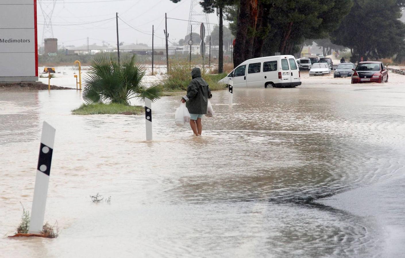 Un hombre intenta cruzar la carretera en Orihuela (Alicante), localidad muy afectada por las inundaciones.