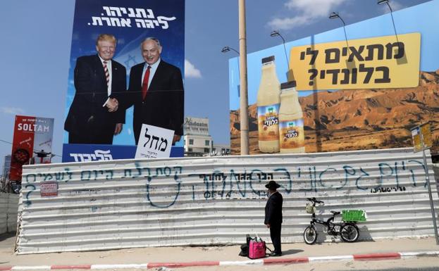 Un judío ultraortodoxo observa un cartel de campaña de Netanyahu en el que aparece junto a Donald Trump en Bnei Brak.