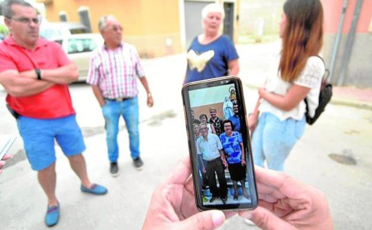 Una vecina muestra en su móvil una fotografía de los ancianos asesinados en Sangonera la Seca (Murcia).