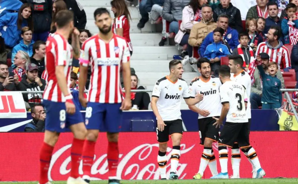 Los futbolistas del Valencia celebran el gol de Parejo, ante la desolación de los atléticos. 