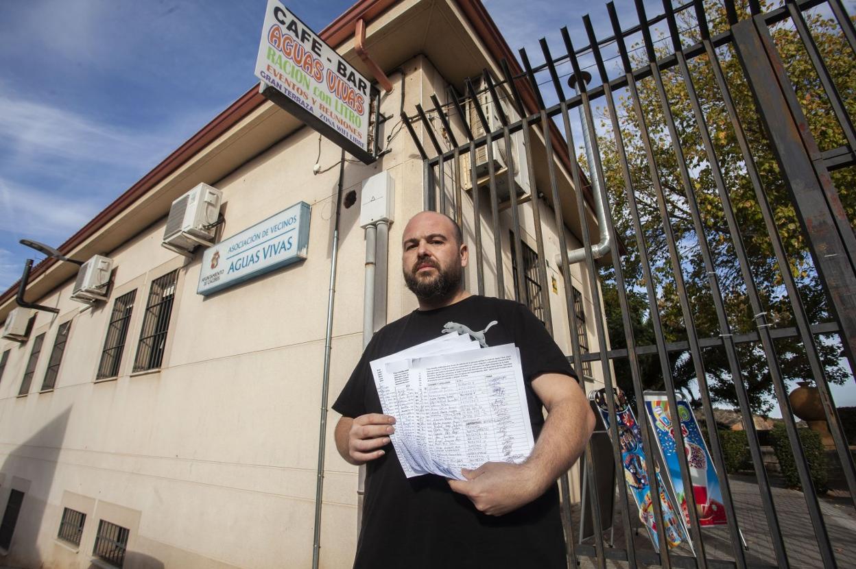 Alberto Redondo muestra en la puerta del bar de la sede vecinal de Aguas Vivas las firmas recogidas. :: jorge rey