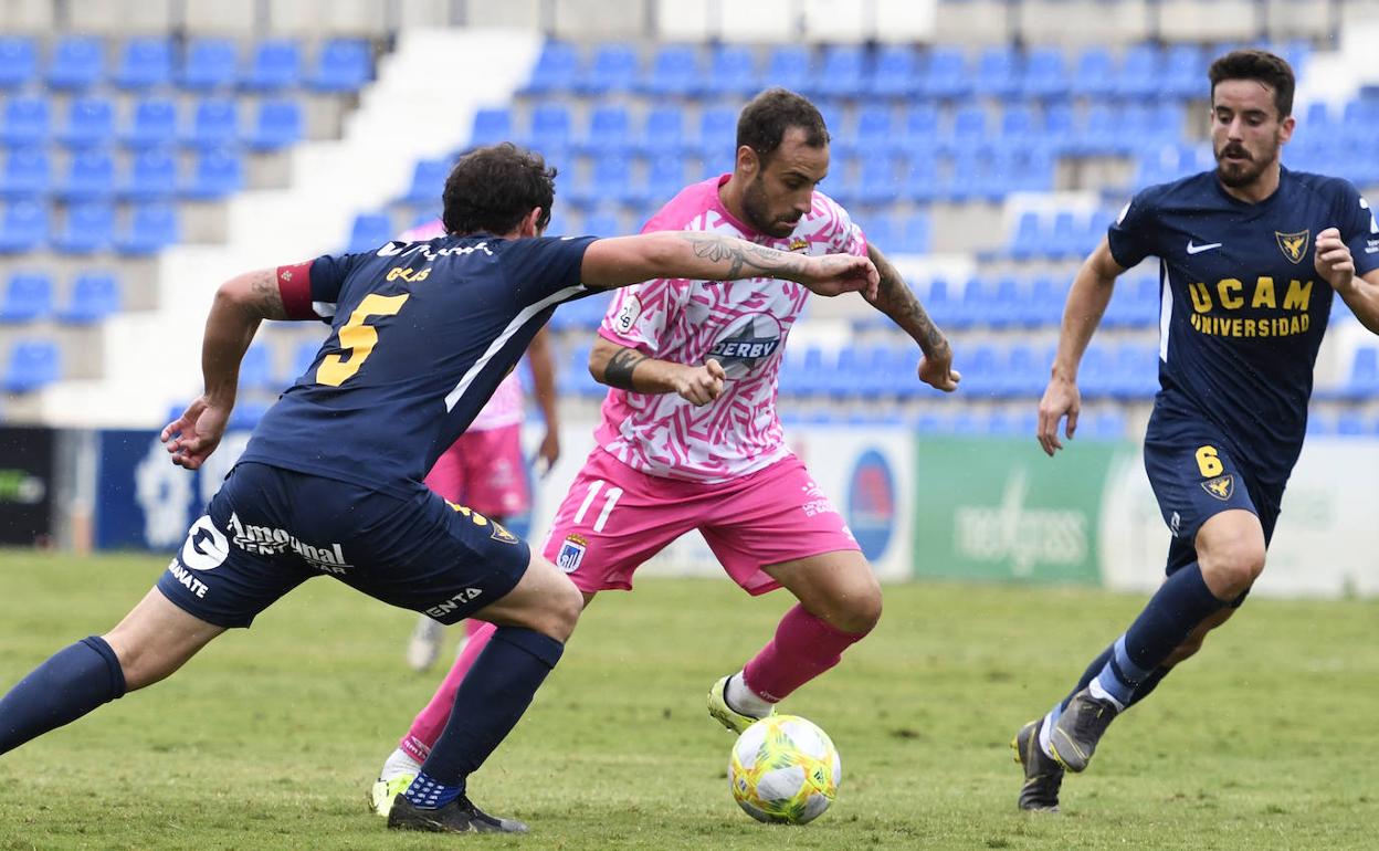 Gorka Santamaría trata de controlar el balón ante dos contrarios en el choque disputado ayer ante el UCAM Murcia en La Condomina. 