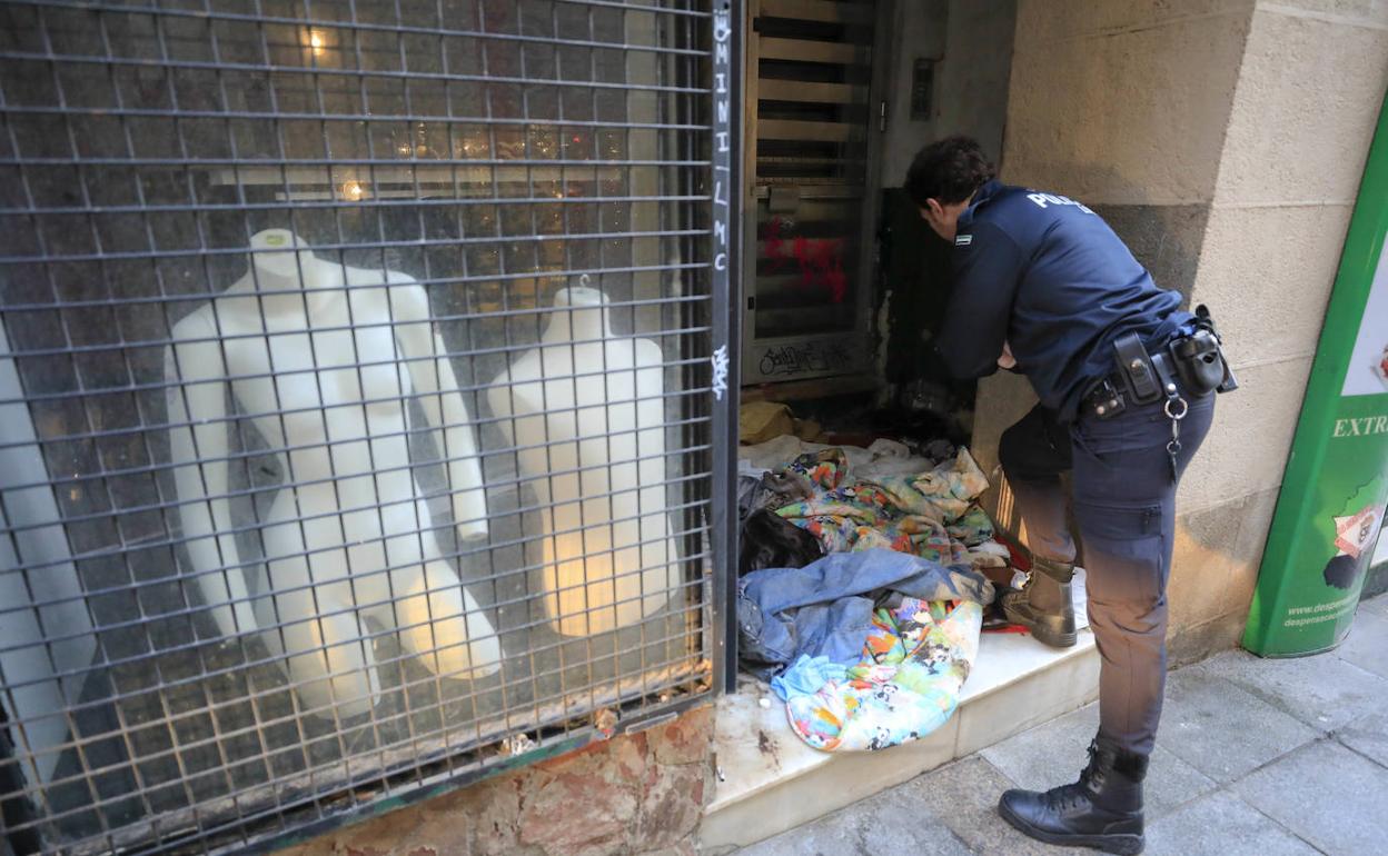 Un agente observa el estado del portal donde dormía el sintecho.