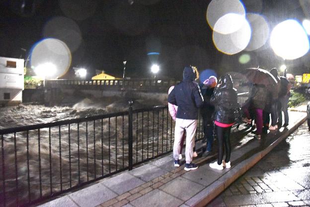 Un grupo de vecinos observa el cauce del río Jerte a su paso por uno de los puentes de la localidad. :: Palma