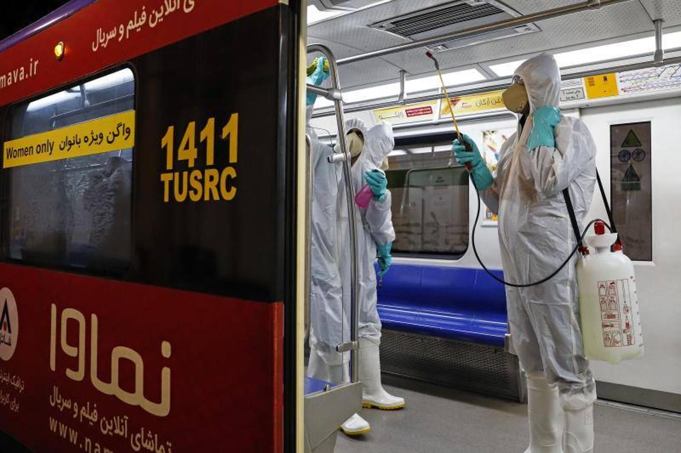 Trabajadores municipales iraníes rocían desinfectante como precaución contra COVID-19 en un vagón del metro público de Teherán