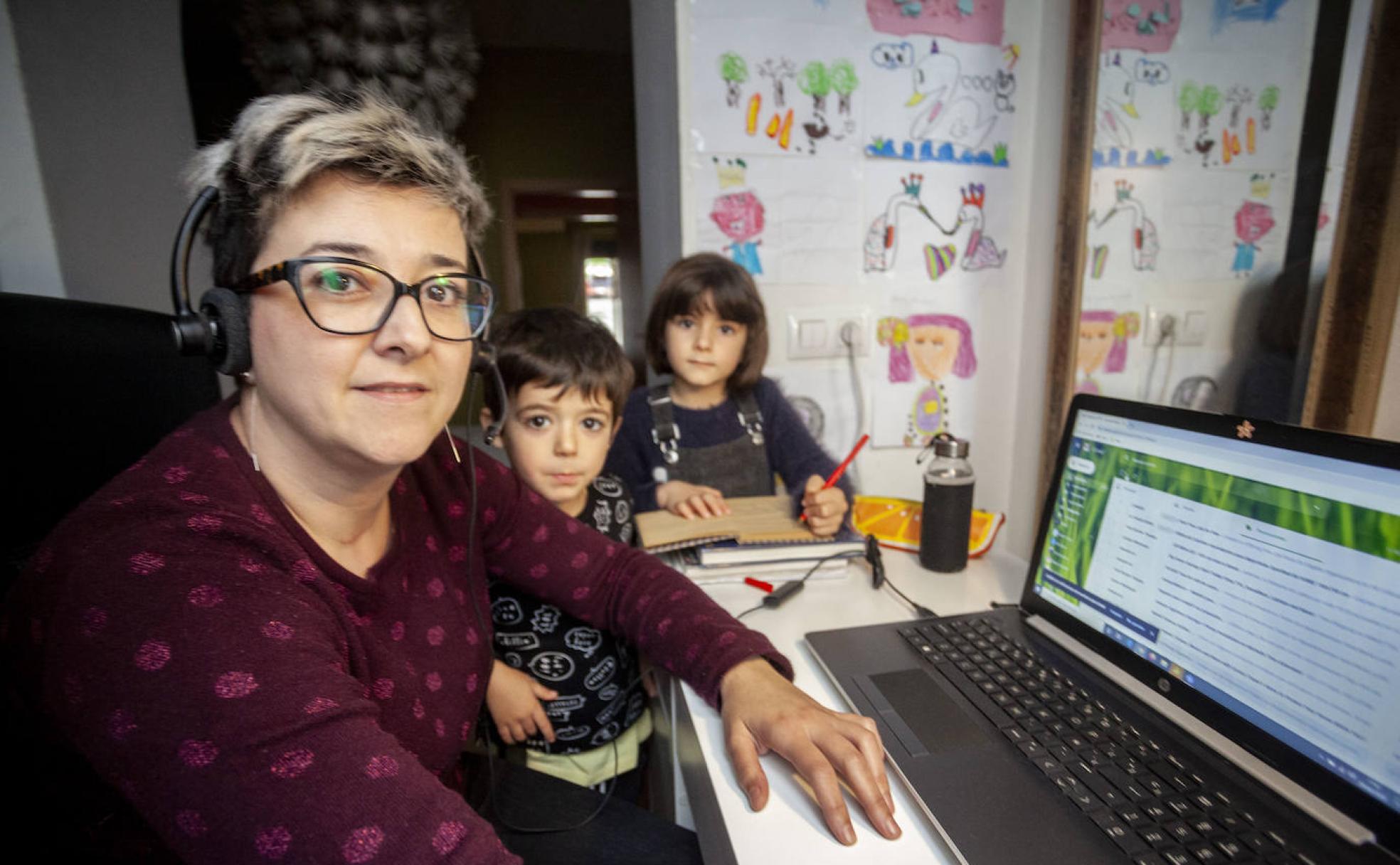 María, que es teleoperadora, atendiendo llamadas desde un vestidor que ha convertido en oficina, con sus hijos al lado.