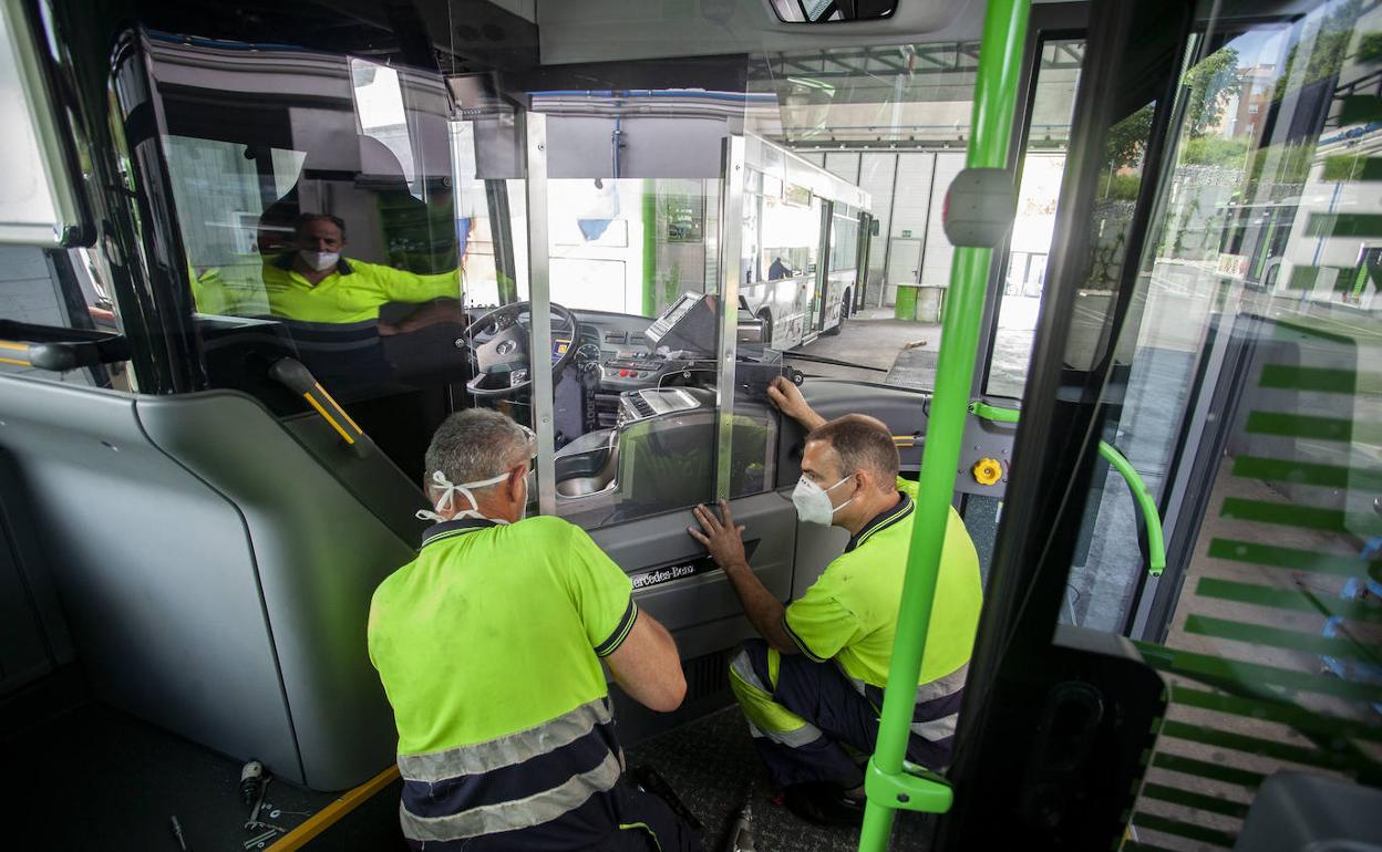 Dos operarios colocando ayer en un autobús la mampara de protección para evitar contagios. 